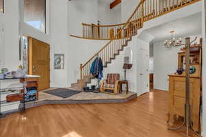 Foyer entrance featuring wood-type flooring, a towering ceiling, and a notable chandelier