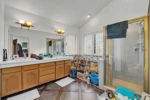 Bathroom featuring tile patterned flooring, lofted ceiling, vanity, and a shower with shower door