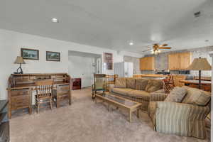 Carpeted living room with ceiling fan and a textured ceiling