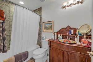 Full bathroom featuring vanity, shower / bath combination with curtain, and toilet