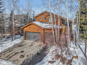 View of snow covered exterior with an outbuilding and a garage