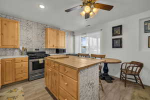 Kitchen featuring light brown cabinets, wooden counters, ceiling fan, a kitchen island, and stainless steel appliances