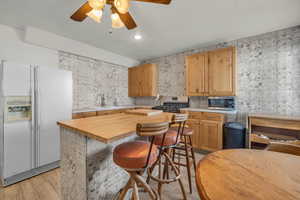 Kitchen with butcher block counters, ceiling fan, sink, light hardwood / wood-style flooring, and appliances with stainless steel finishes