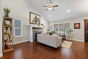Living room featuring a tile fireplace, ceiling fan, high vaulted ceiling, and dark hardwood / wood-style floors