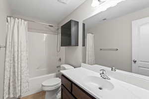 Full bathroom with shower / bath combo, vanity, tile patterned flooring, toilet, and a textured ceiling