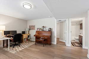 Office area with a textured ceiling and light hardwood / wood-style flooring