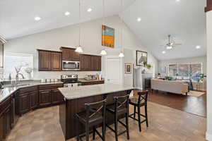 Kitchen with ceiling fan, a breakfast bar, a kitchen island, and appliances with stainless steel finishes