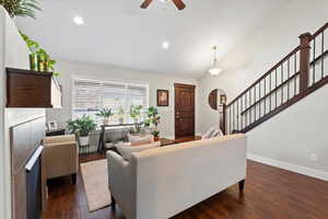Living room featuring ceiling fan, lofted ceiling, and dark wood-type flooring