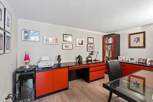 Office area featuring light wood-type flooring and a textured ceiling