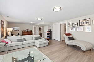 Living room with light wood-type flooring and a textured ceiling