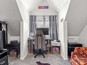 Home office with carpet floors and lofted ceiling