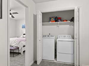 Laundry area featuring washer and dryer, ceiling fan, and light colored carpet