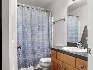 Bathroom featuring vanity, a textured ceiling, toilet, and walk in shower