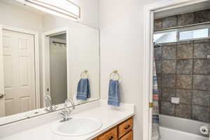 Bathroom featuring quartz countertops, shower / bath combo with shower curtain and vanity