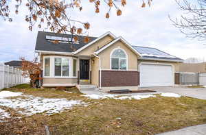 View of front of house with new double pane windows, a garage, a front yard, and solar panels