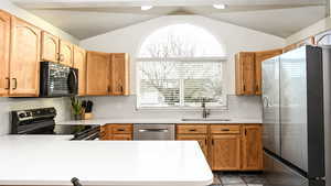 Kitchen with tile backsplash, quartz countertops, sink, stainless steel appliances, and vaulted ceiling