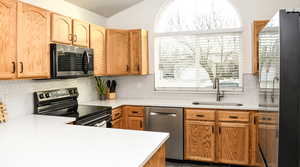 Kitchen with decorative backsplash, quartz countertops, stainless steel appliances, kitchen peninsula, and sink