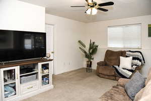 Carpeted living room featuring ceiling fan