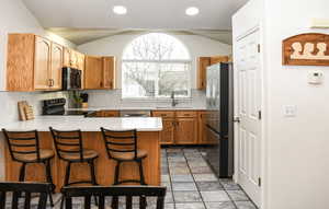 Kitchen featuring sink, beautiful tile backsplash, kitchen peninsula with quartz countertops, a breakfast bar, and appliances with stainless steel finishes