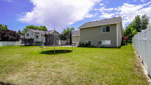 Rear view of house featuring a lawn and a trampoline