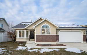 View of front of home featuring solar panels, new double pane windows, and a garage