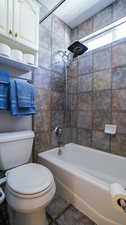 Bathroom with tiled shower / bath combo and toilet