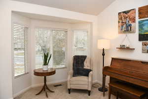 Living area featuring a wealth of natural light, light colored carpet, and lofted ceiling