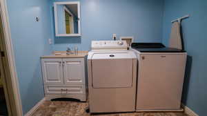 Washroom with cabinets, separate washer and dryer, and sink