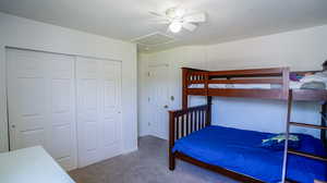 Carpeted bedroom with ceiling fan and a closet