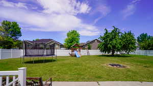 View of yard with a playground and a trampoline