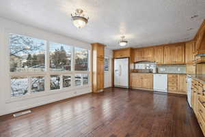 Kitchen featuring decorative backsplash, light stone counters, white appliances, sink, and dark hardwood / wood-style floors