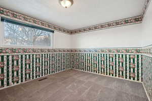 Carpeted empty room with a textured ceiling