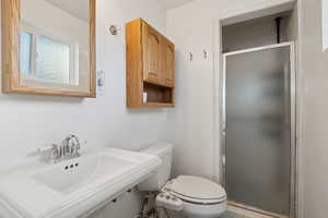 Bathroom with toilet, an enclosed shower, and sink