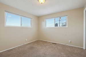 Carpeted spare room featuring a textured ceiling