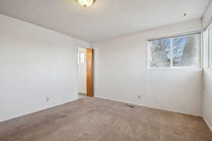 Empty room with light carpet and a textured ceiling