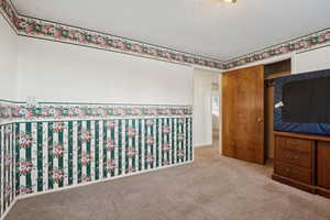 Unfurnished bedroom with light carpet and a textured ceiling