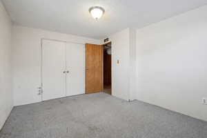 Unfurnished bedroom featuring a textured ceiling and a closet