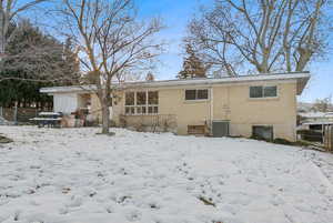 Snow covered rear of property featuring cooling unit