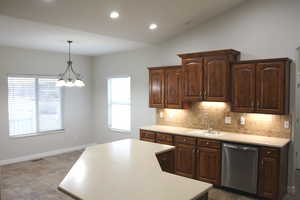 Kitchen with dishwasher, sink, a chandelier, decorative light fixtures, and vaulted ceiling