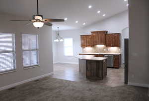 Kitchen featuring a center island, vaulted ceiling, light tile patterned floors, tasteful backsplash, and stainless steel appliances