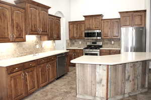 Kitchen featuring sink, a center island, tasteful backsplash, dark brown cabinets, and appliances with stainless steel finishes