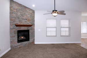 Great room with ceiling fan, a fireplace, carpet floors, and lofted ceiling