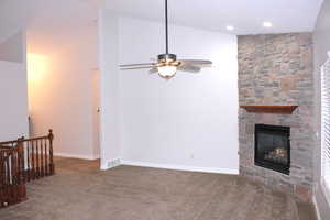 Great room featuring a fireplace, carpet, ceiling fan, and lofted ceiling