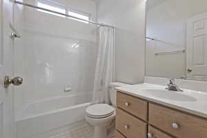 Full bathroom featuring shower / bath combination with curtain, vanity, and toilet