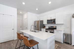 Kitchen featuring white cabinets, sink, an island with sink, and appliances with stainless steel finishes