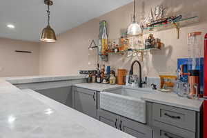 Kitchen featuring gray cabinetry, sink, and decorative light fixtures