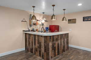 Bar featuring dark wood-type flooring and hanging light fixtures