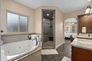 Bathroom featuring ceiling fan, vanity, and shower with separate bathtub