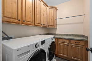 Washroom featuring dark tile patterned flooring, cabinets, and independent washer and dryer