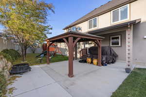 View of patio featuring a gazebo, a playground, and a fire pit